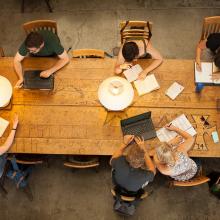 A birds-eye view of students studying individually at a long desk or work table.